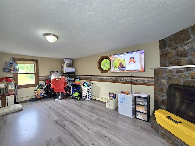 3 Main St, Spencer, MA 01562 - game room with a textured ceiling, wood finished floors, a stone fireplace, and a baseboard heating unit