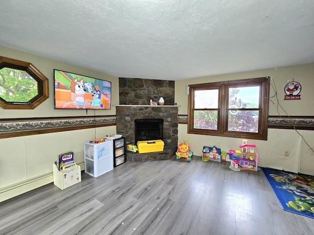 3 Main St, Spencer, MA 01562 - unfurnished living room with wood finished floors, a wainscoted wall, a textured ceiling, baseboard heating, and a fireplace