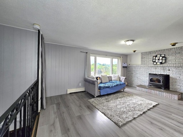 3 Main St, Spencer, MA 01562 - living area with a wood stove, a textured ceiling, a baseboard radiator, and wood finished floors