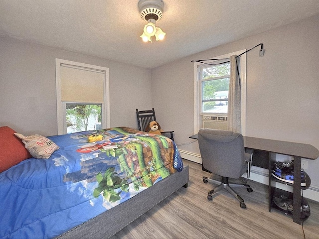 3 Main St, Spencer, MA 01562 - bedroom featuring wood finished floors, multiple windows, cooling unit, and a baseboard radiator