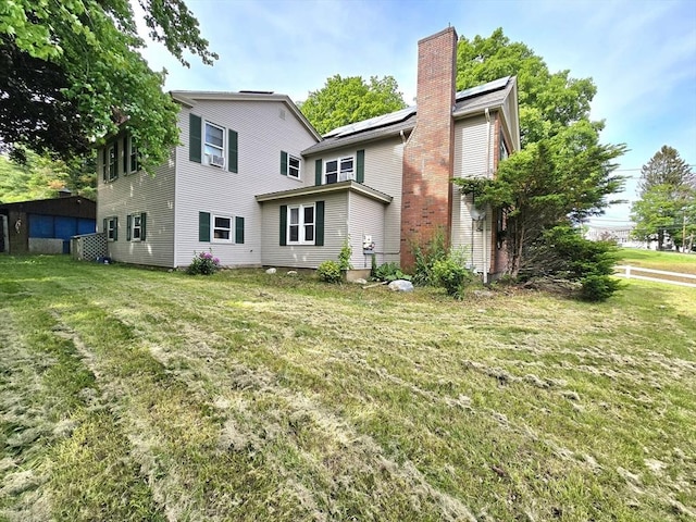 3 Main St, Spencer, MA 01562 - rear view of property featuring a chimney, a lawn, and solar panels