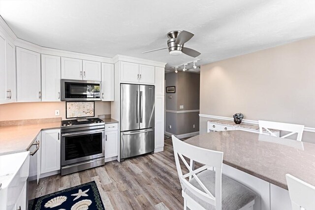 24 Park St, Bourne, MA 02559 - kitchen with white cabinets, stainless steel appliances, ceiling fan, and light wood finished floors