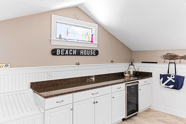 24 Park St, Bourne, MA 02559 - kitchen featuring a wainscoted wall, dark stone counters, white cabinetry, wine cooler, and vaulted ceiling