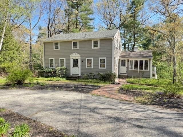 colonial-style house with entry steps and a chimney