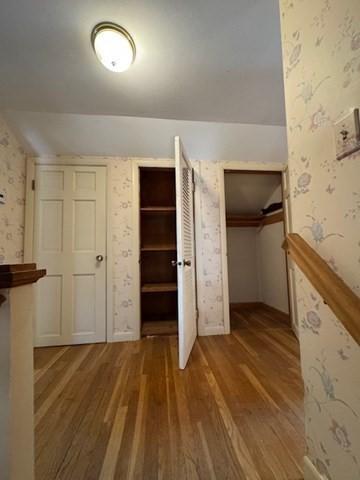 unfurnished bedroom with wallpapered walls and wood finished floors