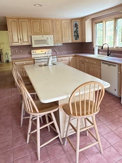 kitchen with light brown cabinetry, a sink, electric range oven, white microwave, and dishwashing machine