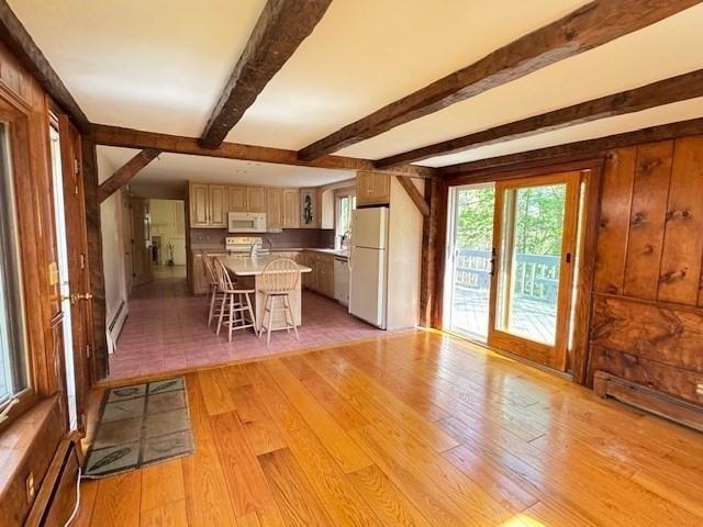 dining room featuring a baseboard radiator, light wood finished floors, and beamed ceiling