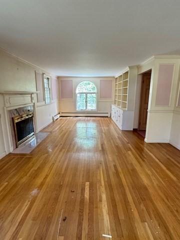 unfurnished living room with crown molding, baseboard heating, a fireplace, and hardwood / wood-style flooring
