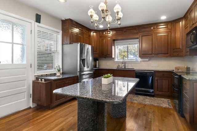 kitchen with hardwood / wood-style flooring, decorative light fixtures, a center island, and black appliances