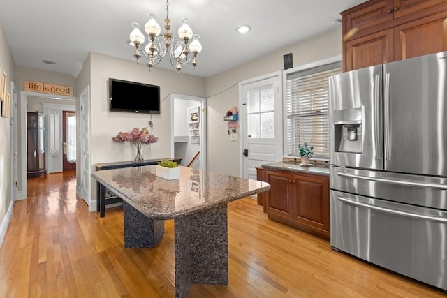 kitchen featuring a breakfast bar area, a center island, stainless steel fridge with ice dispenser, light hardwood / wood-style flooring, and dark stone countertops