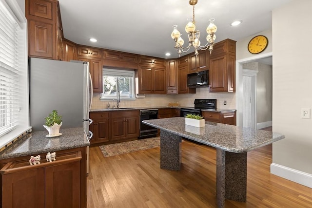 kitchen featuring hanging light fixtures, a kitchen island, sink, and black appliances