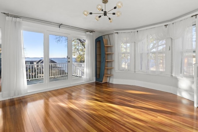 interior space featuring a healthy amount of sunlight, wood-type flooring, and a notable chandelier