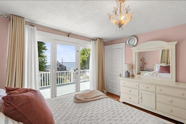 bedroom with a notable chandelier, access to outside, a textured ceiling, and light wood-type flooring