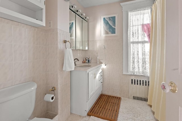 bathroom featuring radiator heating unit, tile walls, vanity, toilet, and tile patterned floors