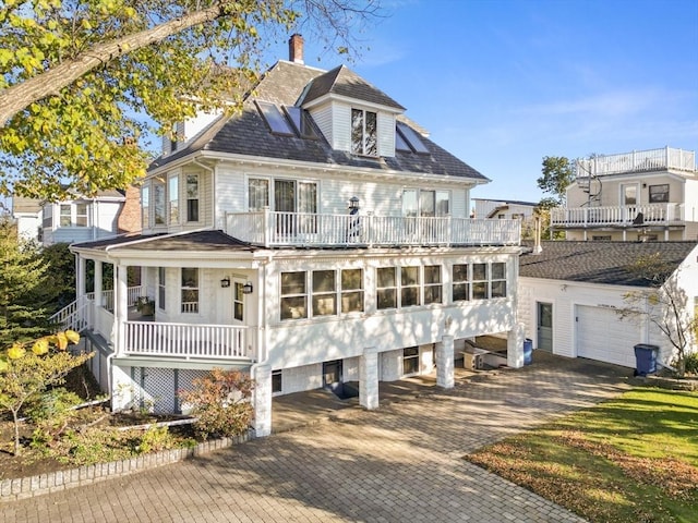 view of front of property with a garage, a balcony, and covered porch