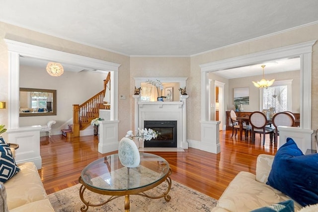 living room featuring crown molding, ornate columns, light hardwood / wood-style flooring, and a notable chandelier