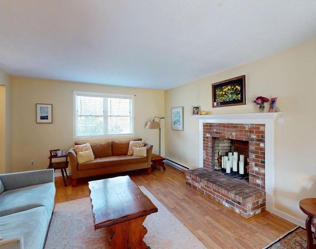 living room featuring a brick fireplace, a baseboard heating unit, and wood finished floors