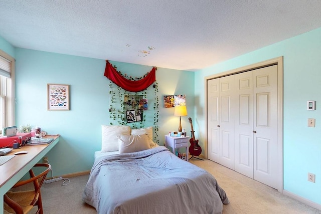 bedroom featuring a closet, a textured ceiling, baseboards, and light carpet