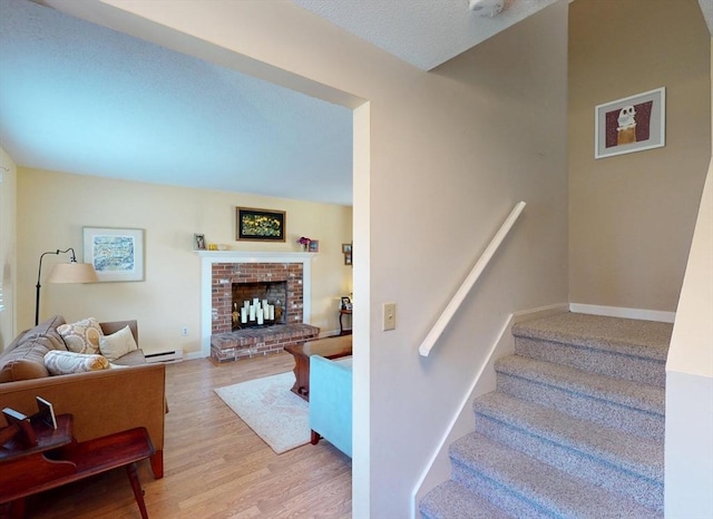 stairs featuring baseboards, a baseboard radiator, a fireplace, and wood finished floors