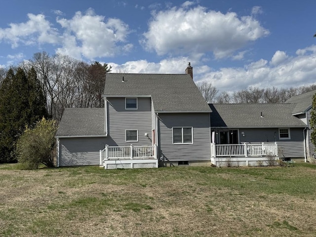 rear view of property with a lawn, a wooden deck, a chimney, and roof with shingles