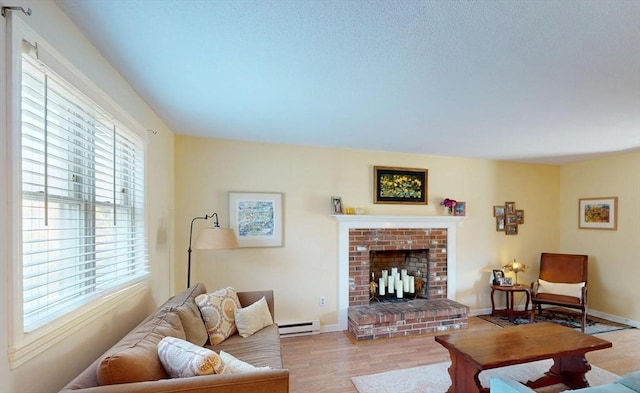 living area featuring baseboards, baseboard heating, a brick fireplace, and wood finished floors