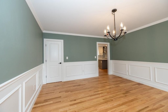 34 Torre St, Reading, MA 01867 - empty room featuring a chandelier, crown molding, wainscoting, light wood-style flooring, and a decorative wall