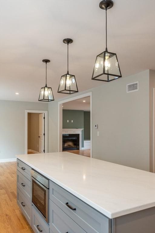 34 Torre St, Reading, MA 01867 - kitchen with gray cabinets, stainless steel microwave, light wood-style floors, light countertops, and recessed lighting