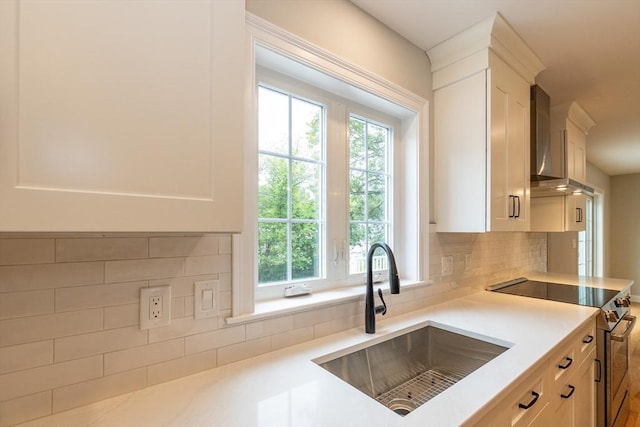 34 Torre St, Reading, MA 01867 - kitchen with high end stainless steel range oven, wall chimney range hood, light countertops, tasteful backsplash, and white cabinetry