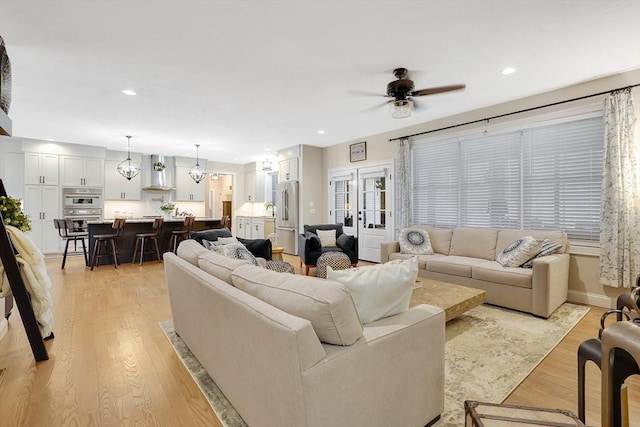 living room with light hardwood / wood-style floors, french doors, and ceiling fan