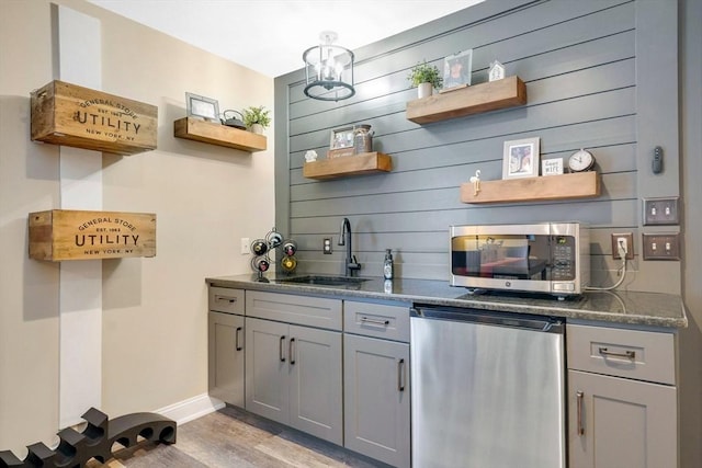 kitchen with sink, appliances with stainless steel finishes, gray cabinetry, a chandelier, and light wood-type flooring