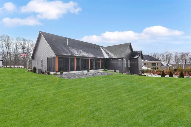 rear view of house featuring a sunroom and a lawn