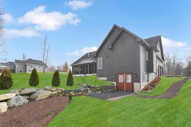 view of home's exterior with a yard, a patio area, and a sunroom