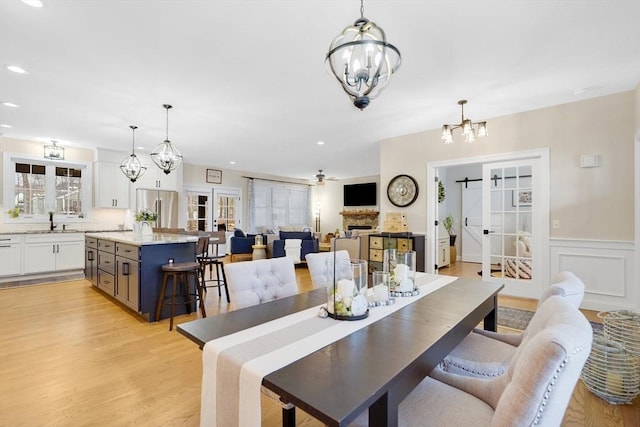 dining space featuring plenty of natural light, sink, light wood-type flooring, and a notable chandelier