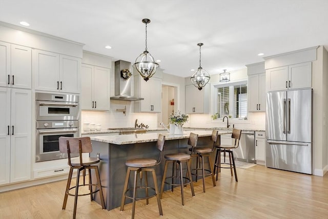 kitchen featuring a kitchen island, decorative light fixtures, white cabinetry, stainless steel appliances, and light stone countertops