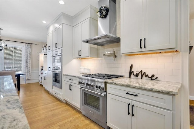 kitchen with white cabinetry, pendant lighting, wall chimney exhaust hood, and appliances with stainless steel finishes