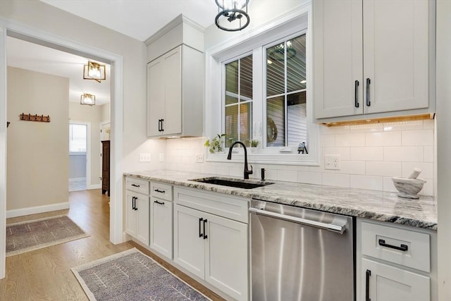 kitchen featuring sink, white cabinetry, dishwasher, light stone countertops, and light hardwood / wood-style floors