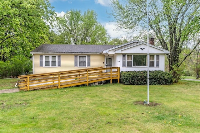view of front of home with a deck, a front lawn, and a chimney