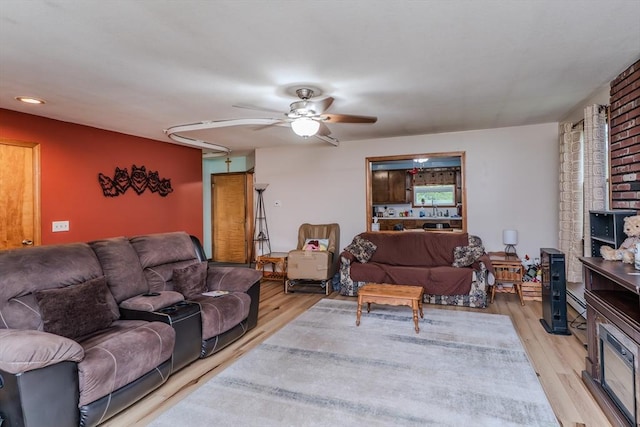 living area featuring a ceiling fan, light wood finished floors, and a wood stove