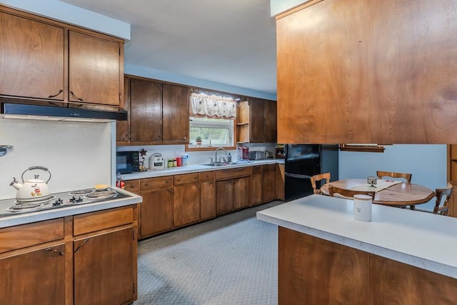 kitchen featuring a sink, under cabinet range hood, electric cooktop, freestanding refrigerator, and light countertops