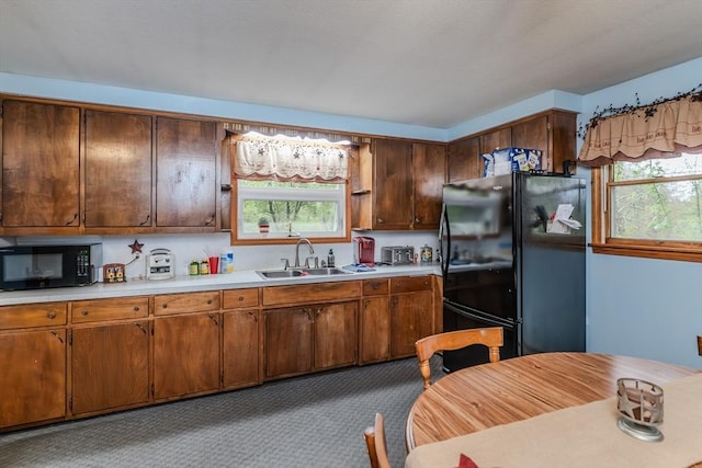 kitchen featuring black appliances, a sink, and light countertops