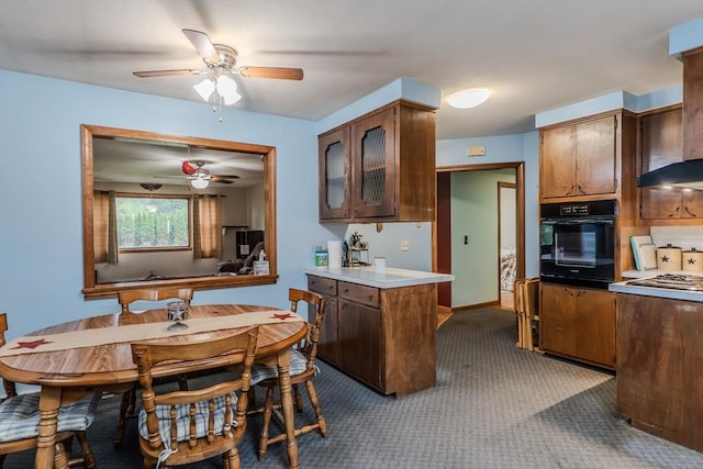 kitchen with oven, a ceiling fan, light carpet, light countertops, and glass insert cabinets