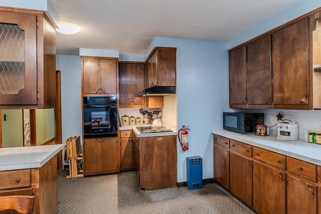 kitchen with black appliances, light countertops, under cabinet range hood, and light carpet