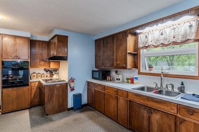 kitchen featuring black appliances, a sink, light countertops, and under cabinet range hood