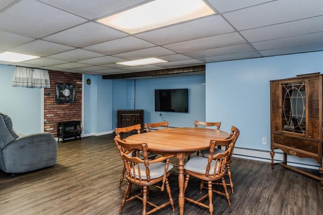 dining area featuring wood finished floors, a drop ceiling, baseboards, and a fireplace