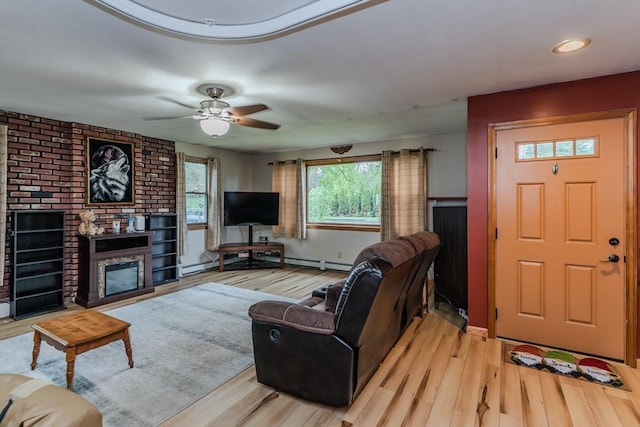 living room featuring a fireplace, wood finished floors, a ceiling fan, and baseboards