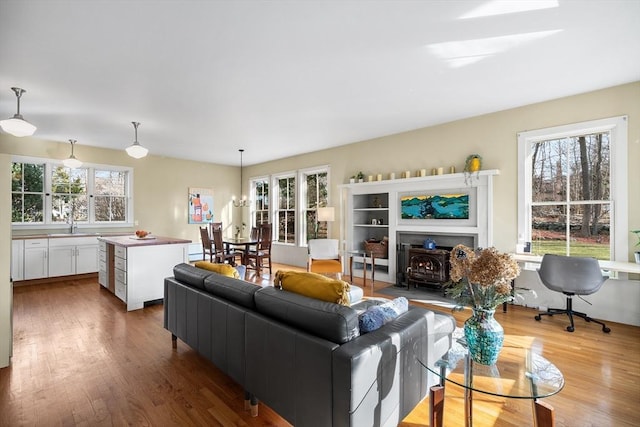 living room featuring hardwood / wood-style flooring, a wood stove, sink, and a chandelier