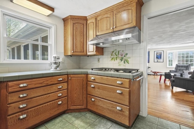 25 Cardigan Rd, Tewksbury, MA 01876 - kitchen with under cabinet range hood, stainless steel gas stovetop, backsplash, brown cabinets, and open floor plan