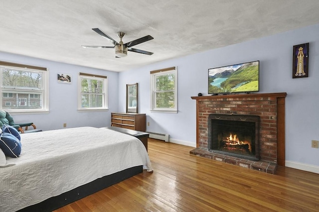 25 Cardigan Rd, Tewksbury, MA 01876 - bedroom featuring baseboard heating, hardwood / wood-style floors, baseboards, and a brick fireplace