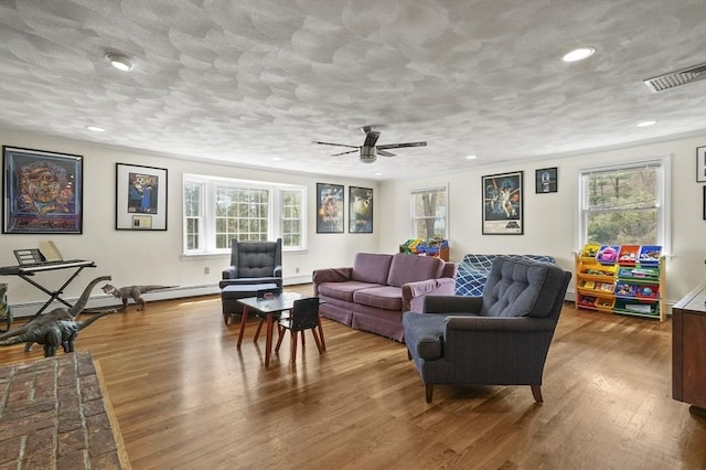 25 Cardigan Rd, Tewksbury, MA 01876 - living room featuring wood finished floors, a baseboard heating unit, a ceiling fan, and recessed lighting
