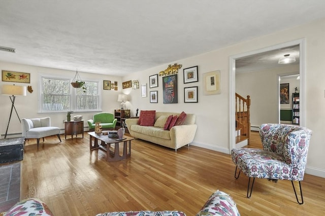 25 Cardigan Rd, Tewksbury, MA 01876 - living area with wood finished floors, stairway, a baseboard heating unit, and baseboards